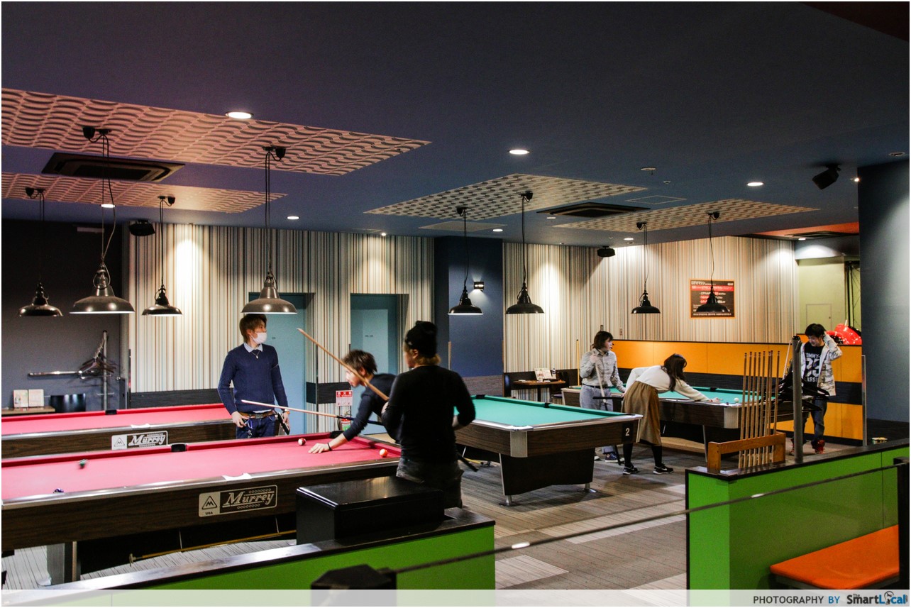 The Smart Local - Several people playing billiards and pool in the arcade