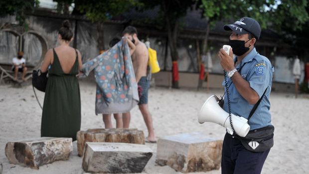 Bali official uses a megaphone to tell tourists to stay inside