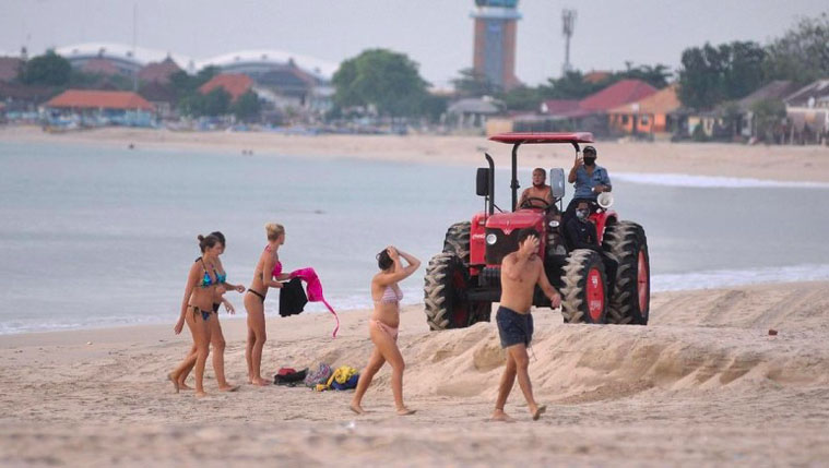 Bali officials hop on a tractor to shoo beachgoers away