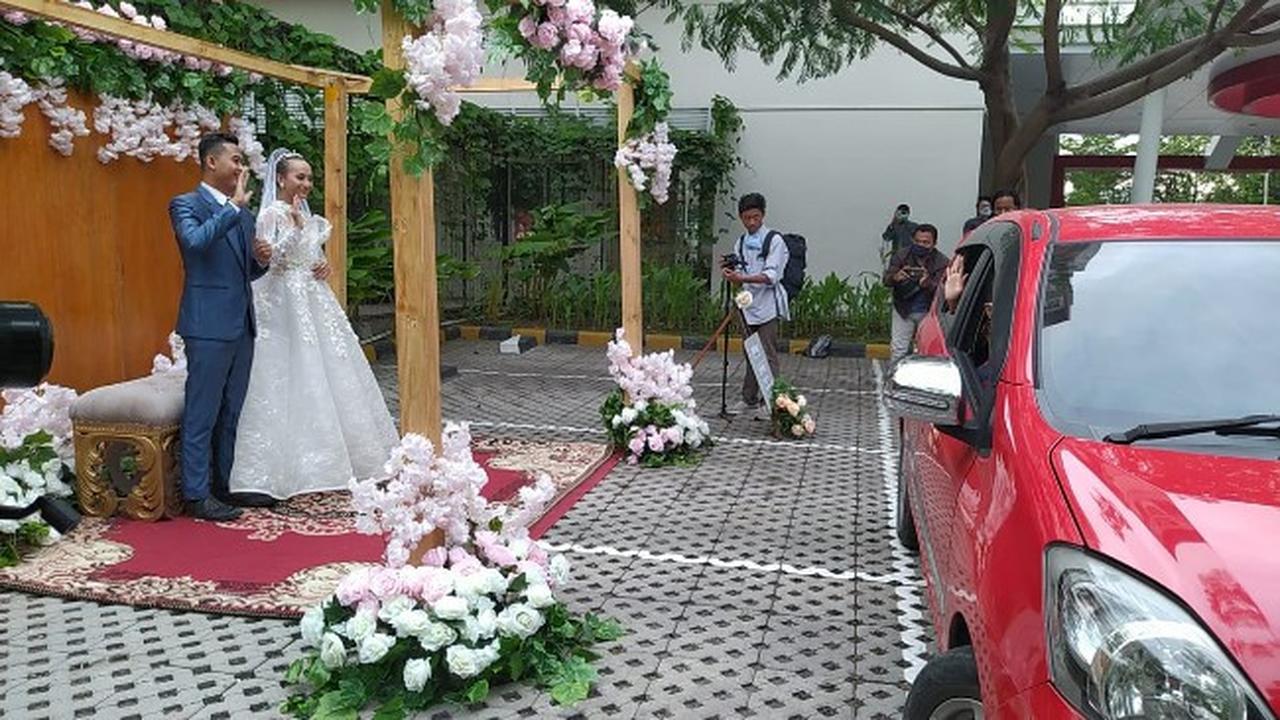 Couple waves to guest at drive-thru wedding