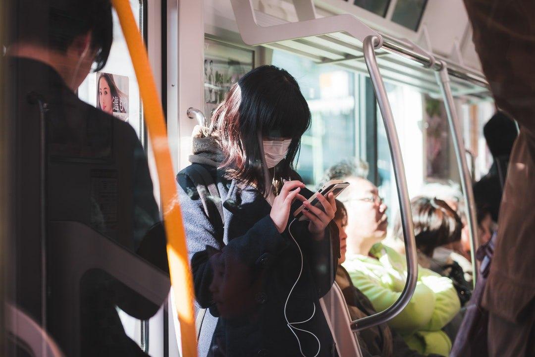 Putting on a pair of earpiece while in a train in Japan