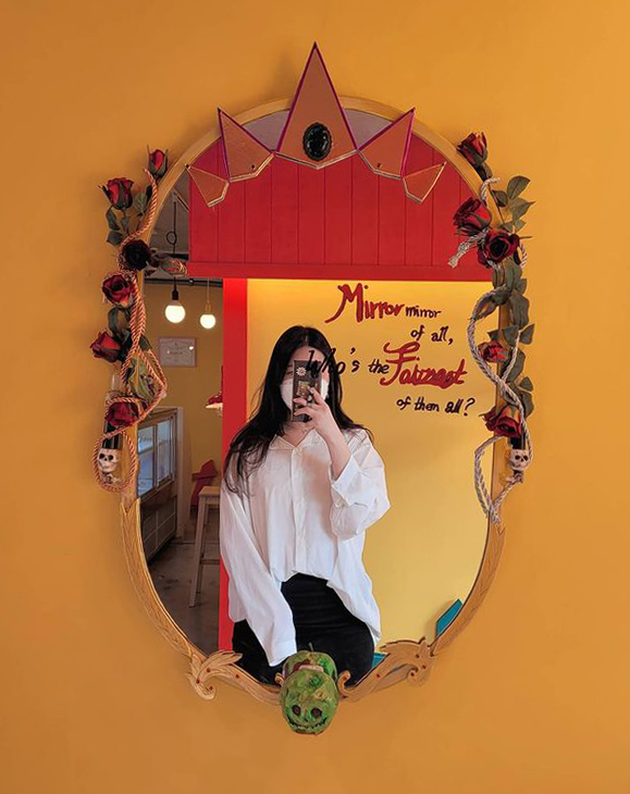 woman taking a mirror selfie in front of snow white-themed mirror