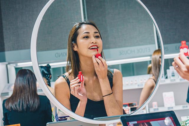 woman putting on lipstick with a mirror