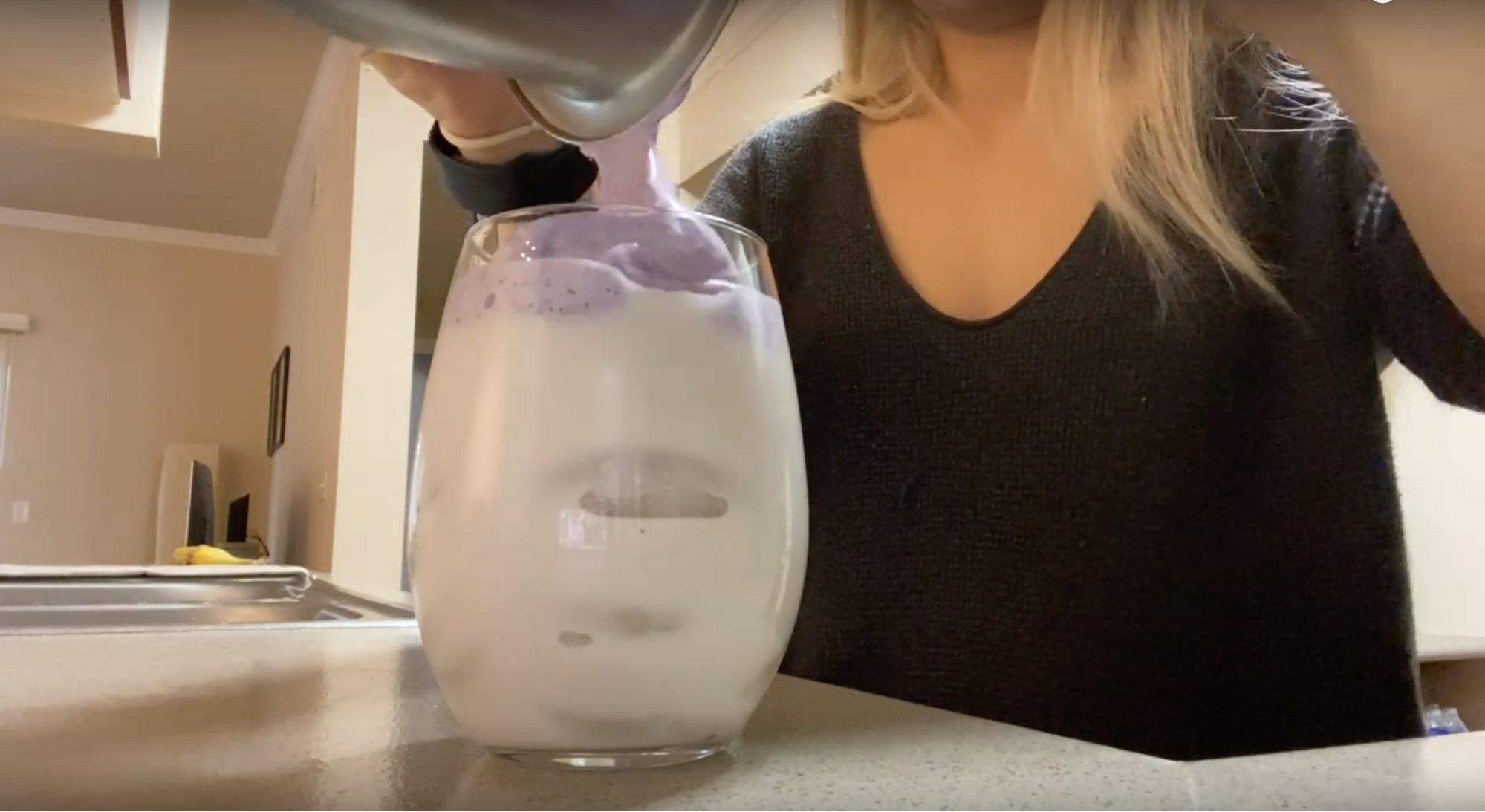 girl pouring purple ube foam onto a glass of milk