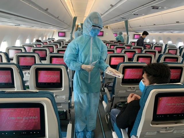 passengers on vietnamese plane with attendant in ppe