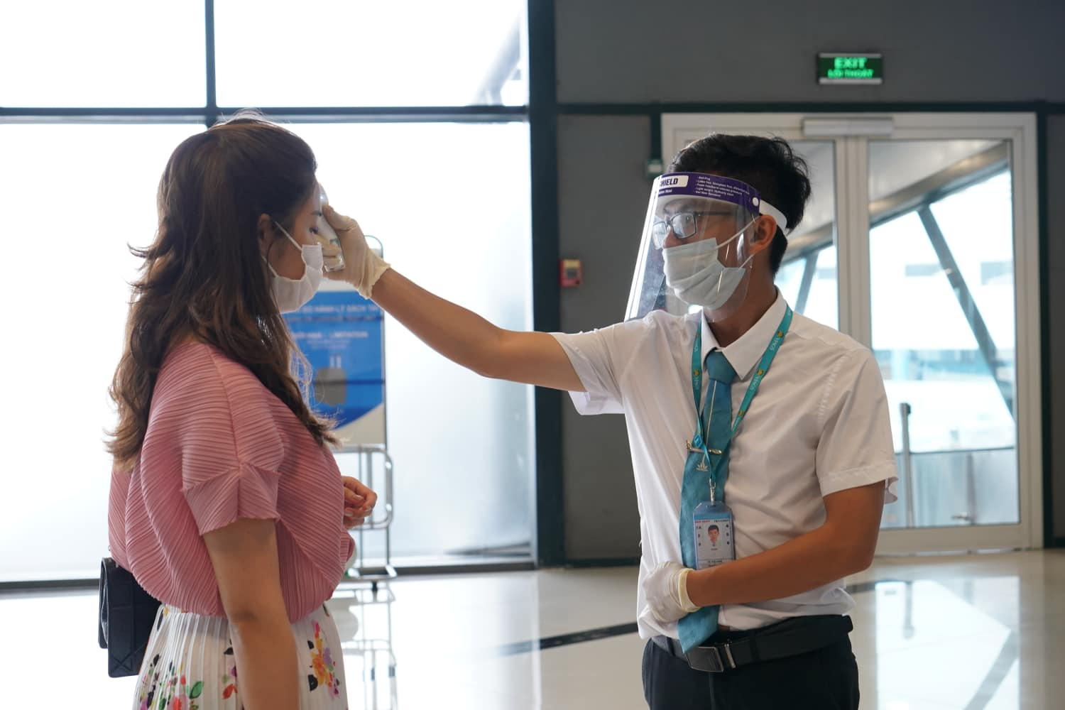 flights to Vietnam - airport staff taking passenger's temperature
