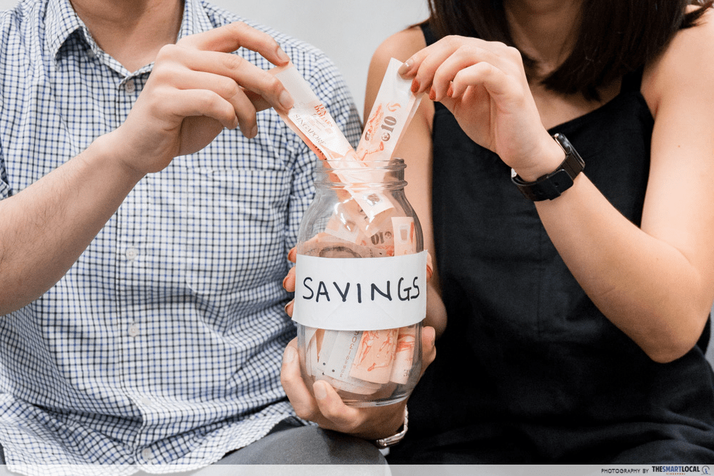 Couple putting money into savings jar