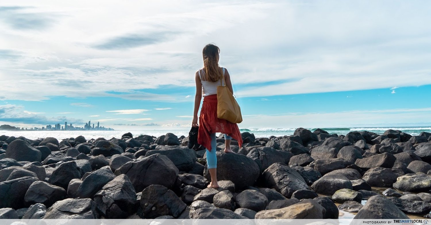 solo travels near singapore female walking on rocks on the beach