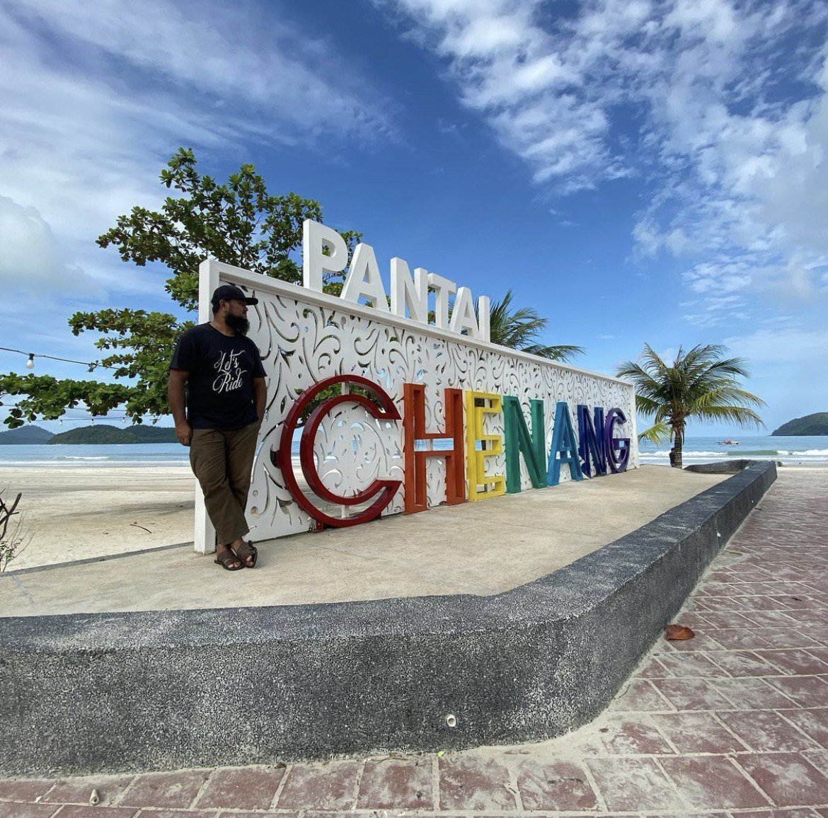 talent posing at signage of beach 