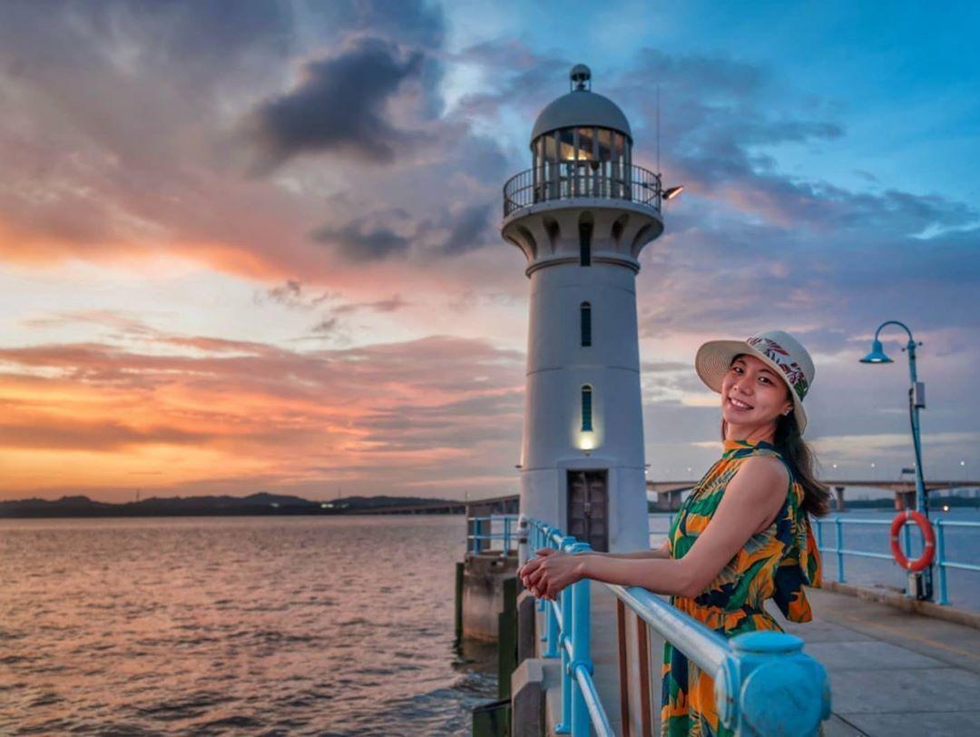 talent posing at Raffles Marina Lighthouse during golden hour