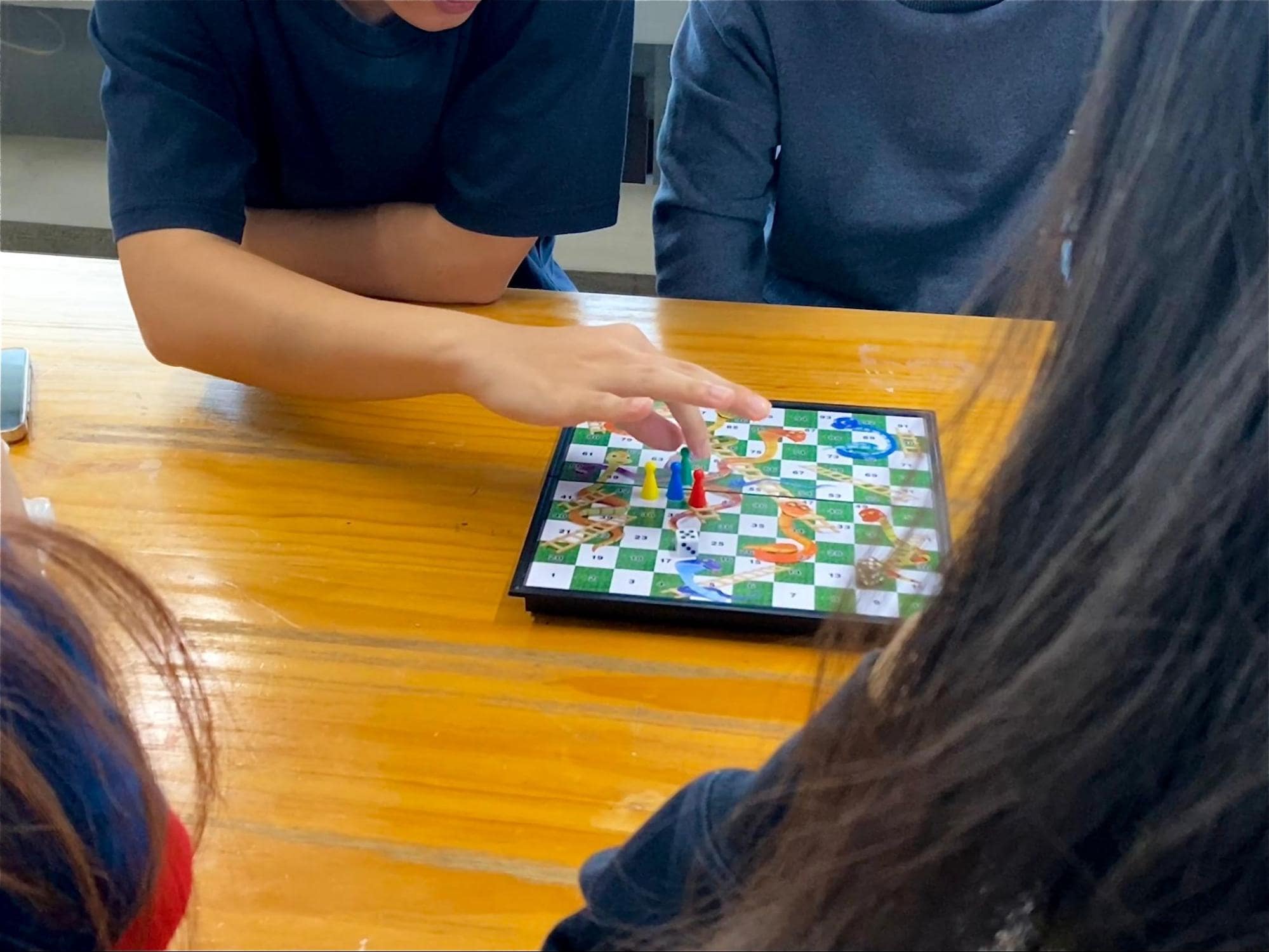 four people playing a round of Snakes & Ladders