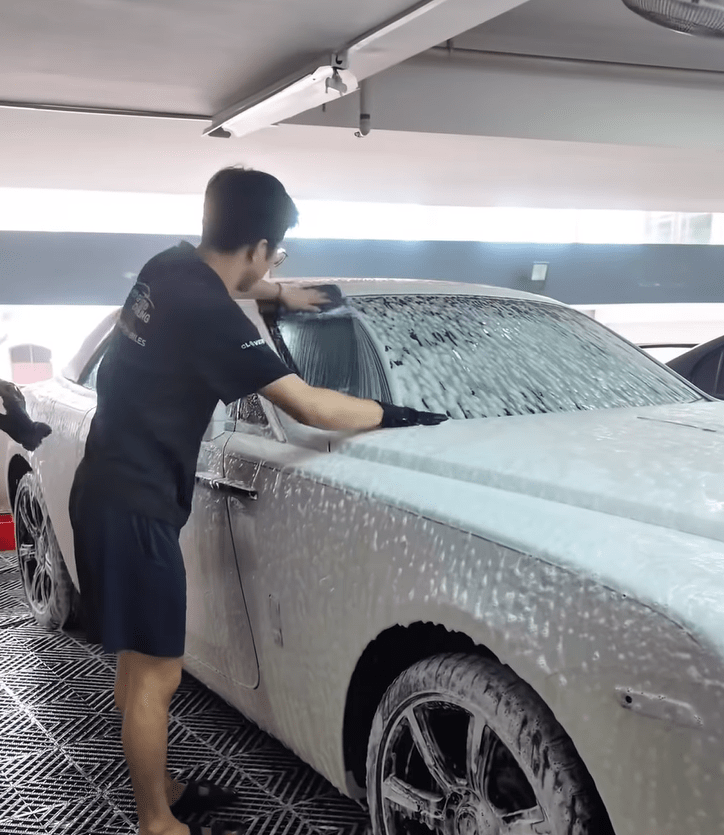 A Carlogy worker wipes a car windshield