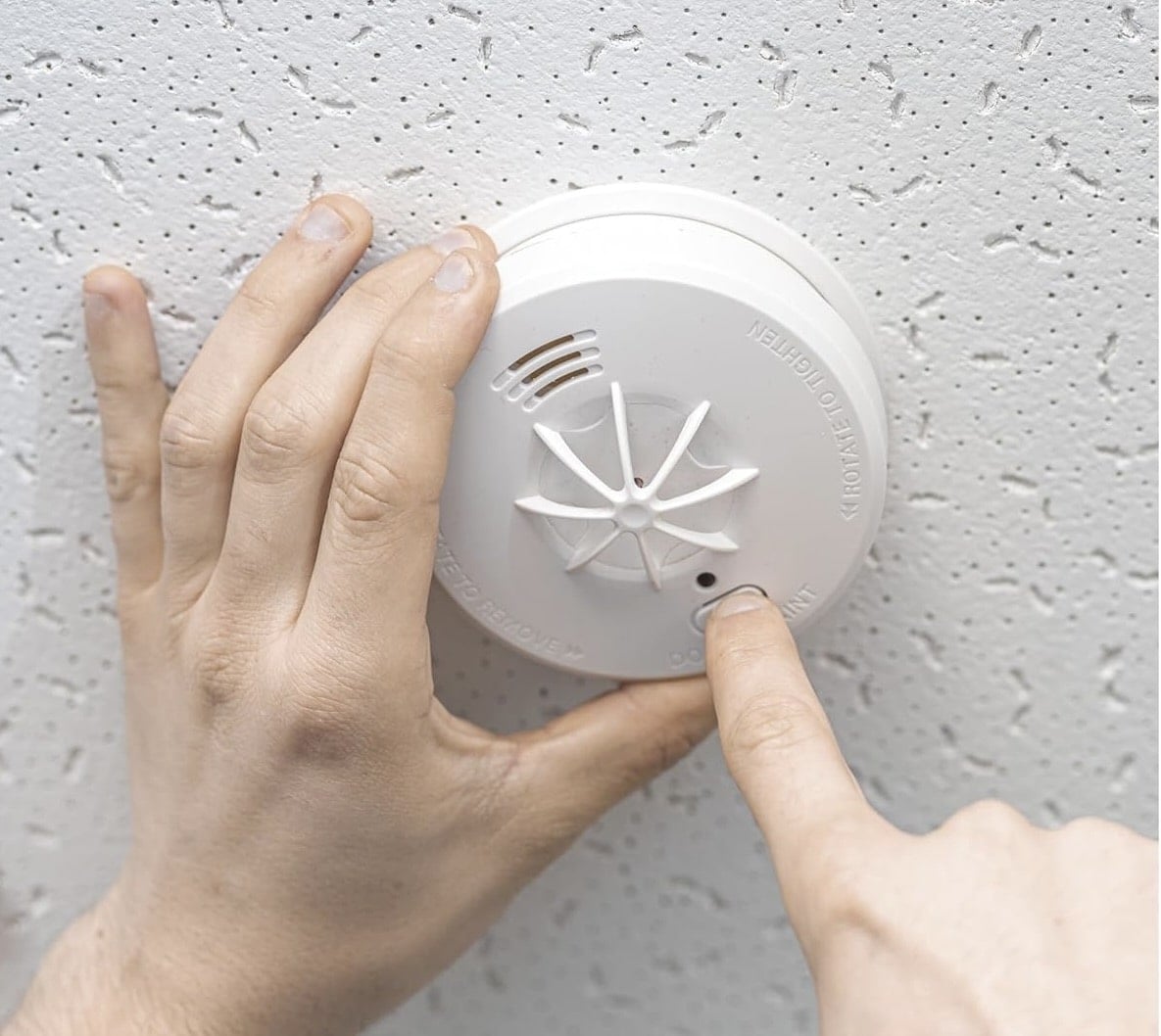 home fire - hand pressing button on heat detector