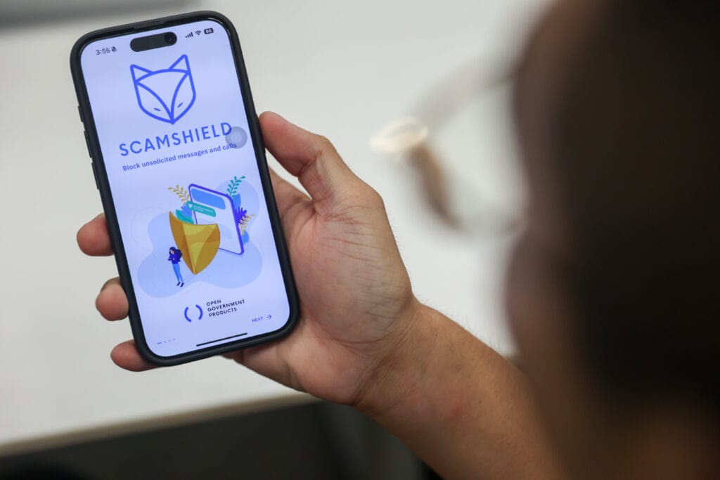 tiktok livestream - hand holding phone with scamshield app