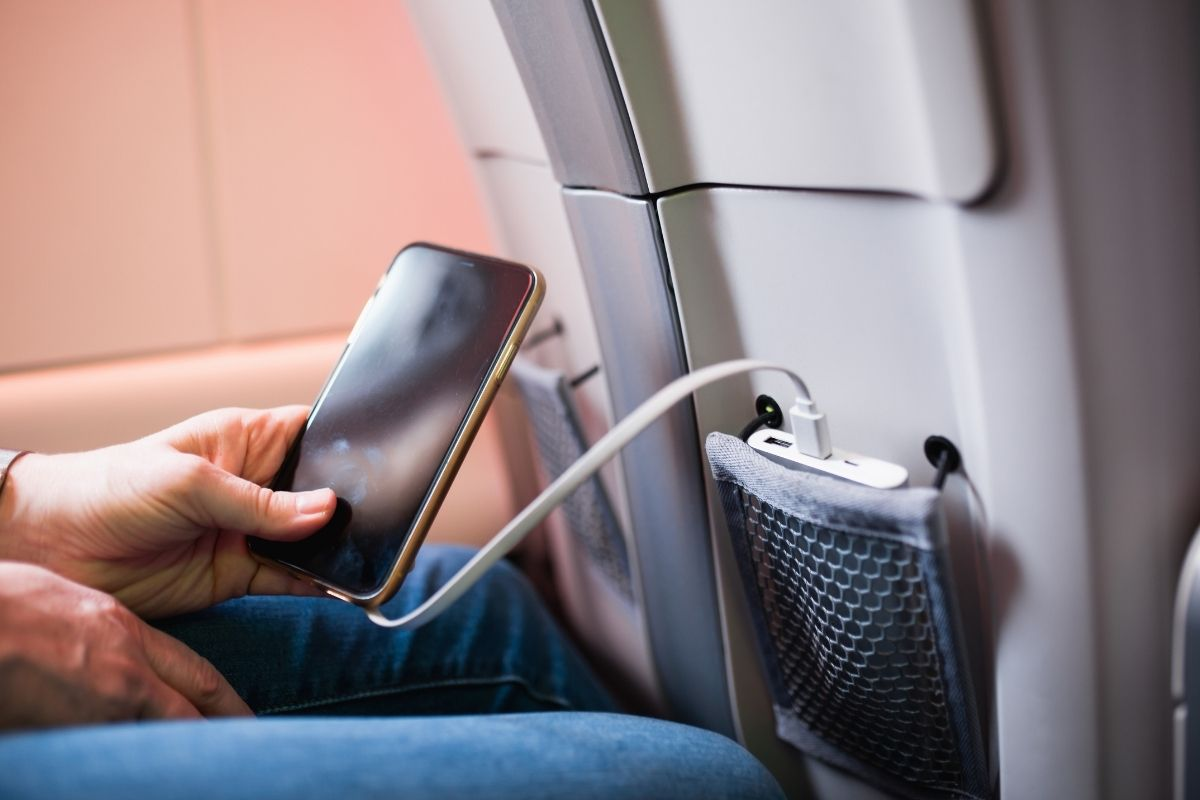 Person charging phone using power bank on flight